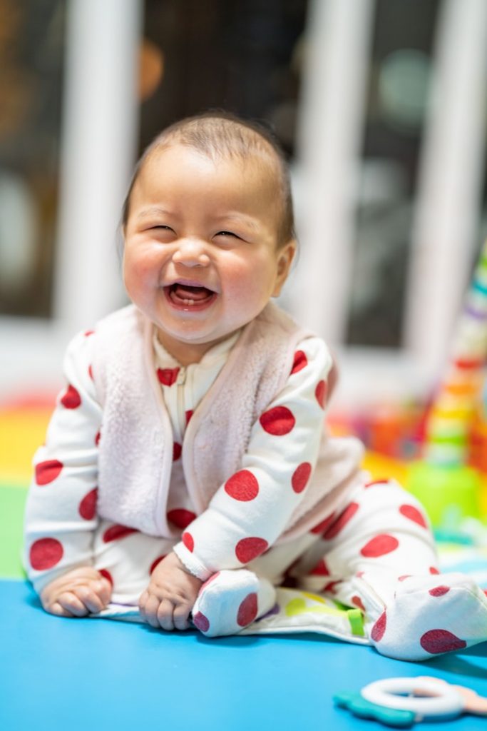 A photograph of a smiling baby in a polka-dot onesie.