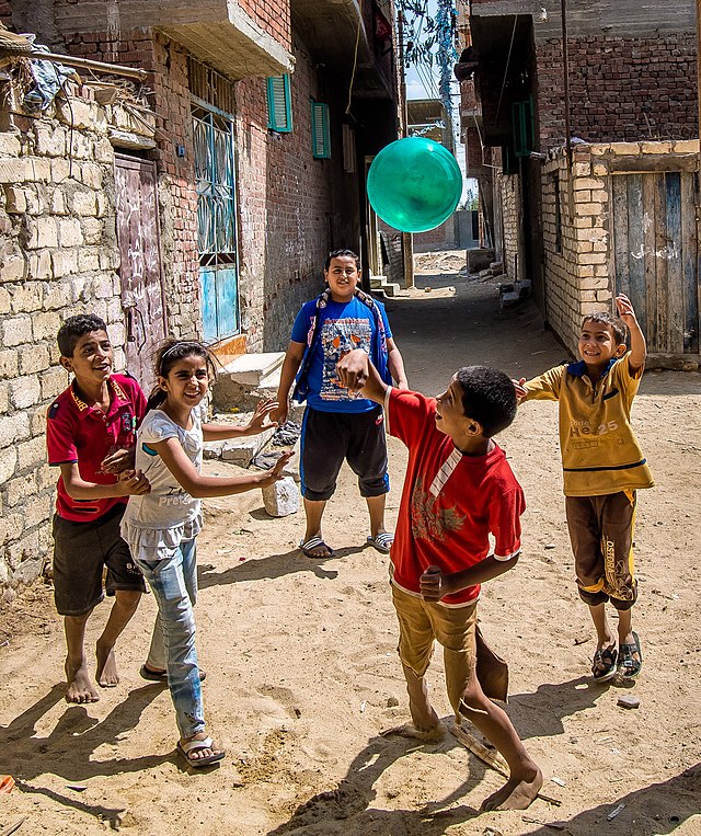 Five children playing with a green ball