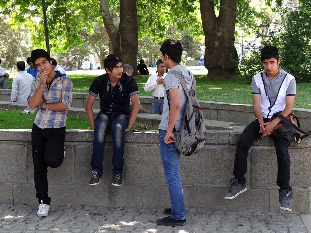A group of teenage boys sitting on a concrete wall.