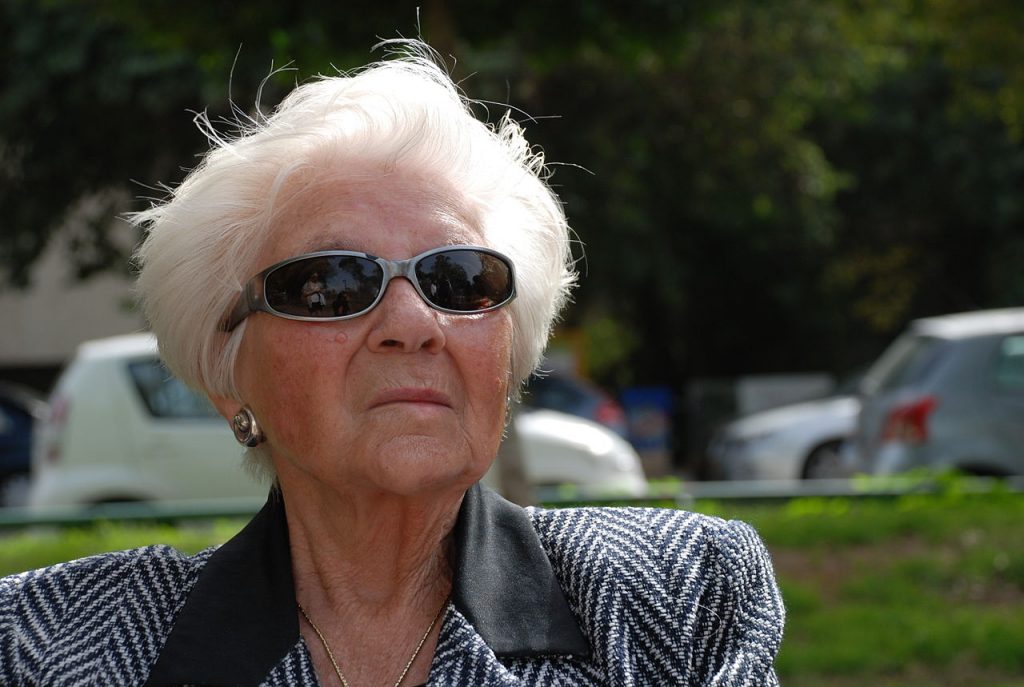 An old woman sitting outside wearing sunglasses