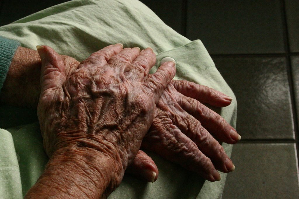 An older person's hands resting on their lap.
