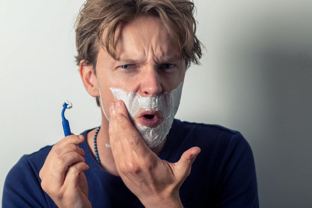 A man shaving himself with a razor