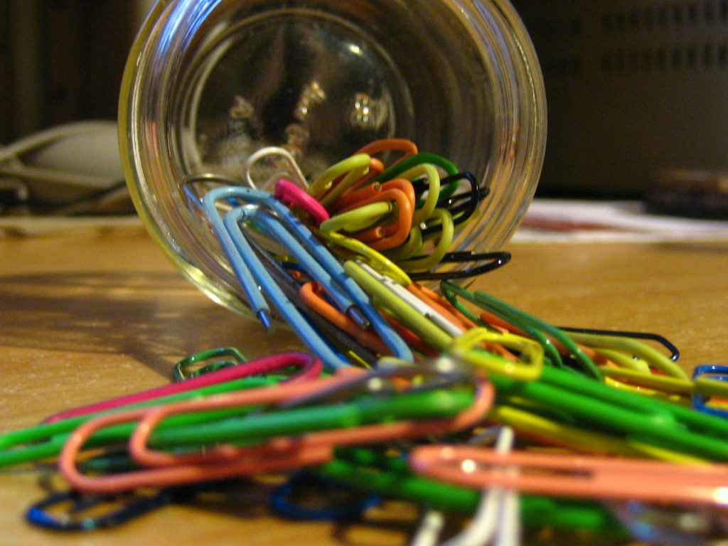 A jar tipped over spilling paperclips