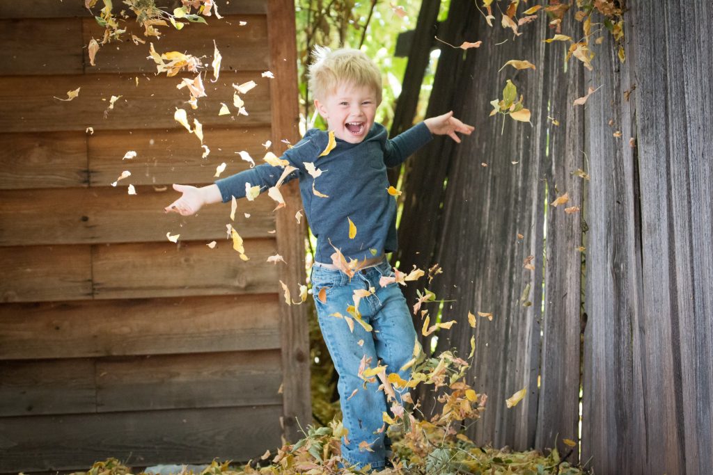 A boy jumping into a pile of leaves