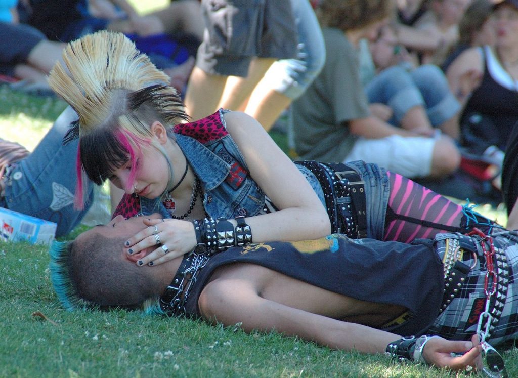 A couple lying on the ground with coloured hair and punk jewelry
