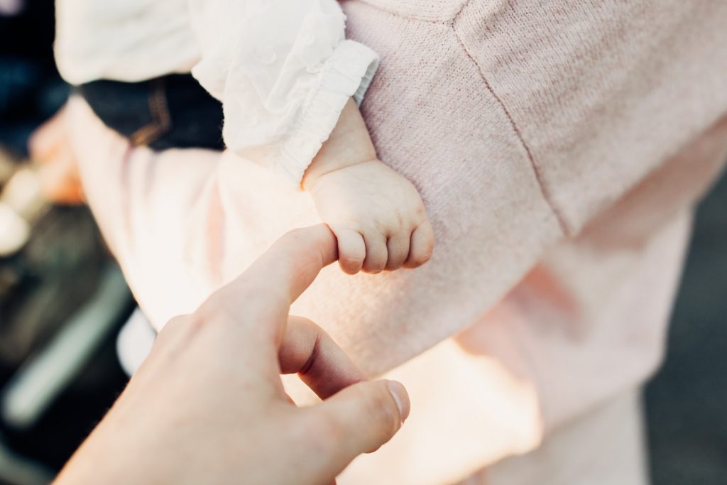 A baby grasping an adult's finger