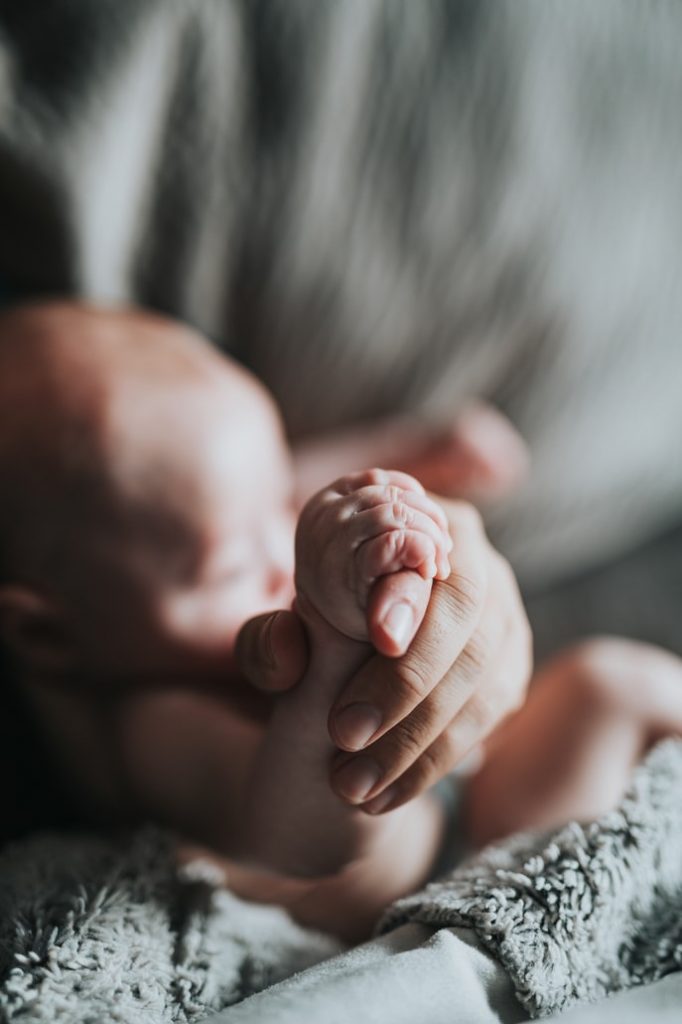 An image of a baby using the pincer grasp to hold an adult's finger