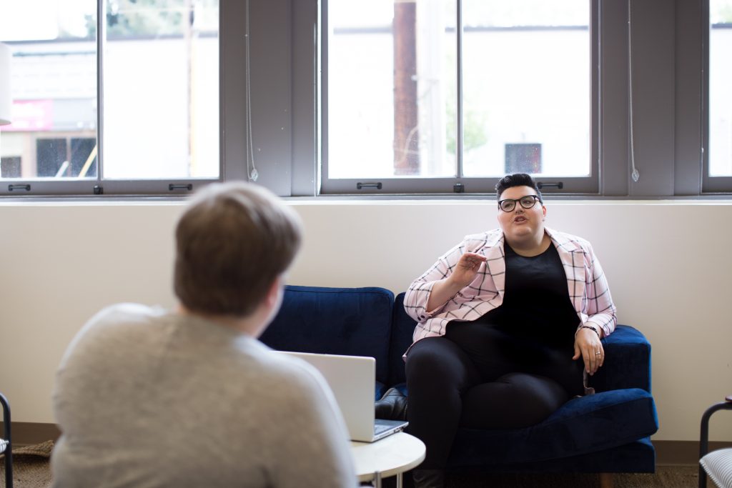 A person sitting on a couch communicating with someone across the room