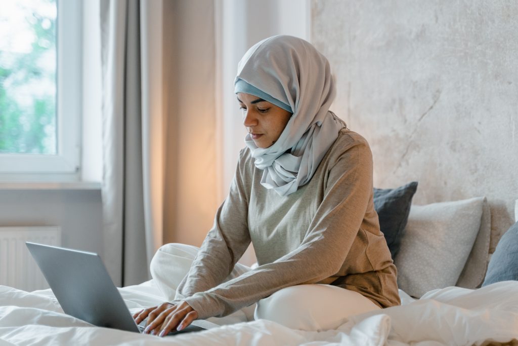 Person using laptop on bed. 