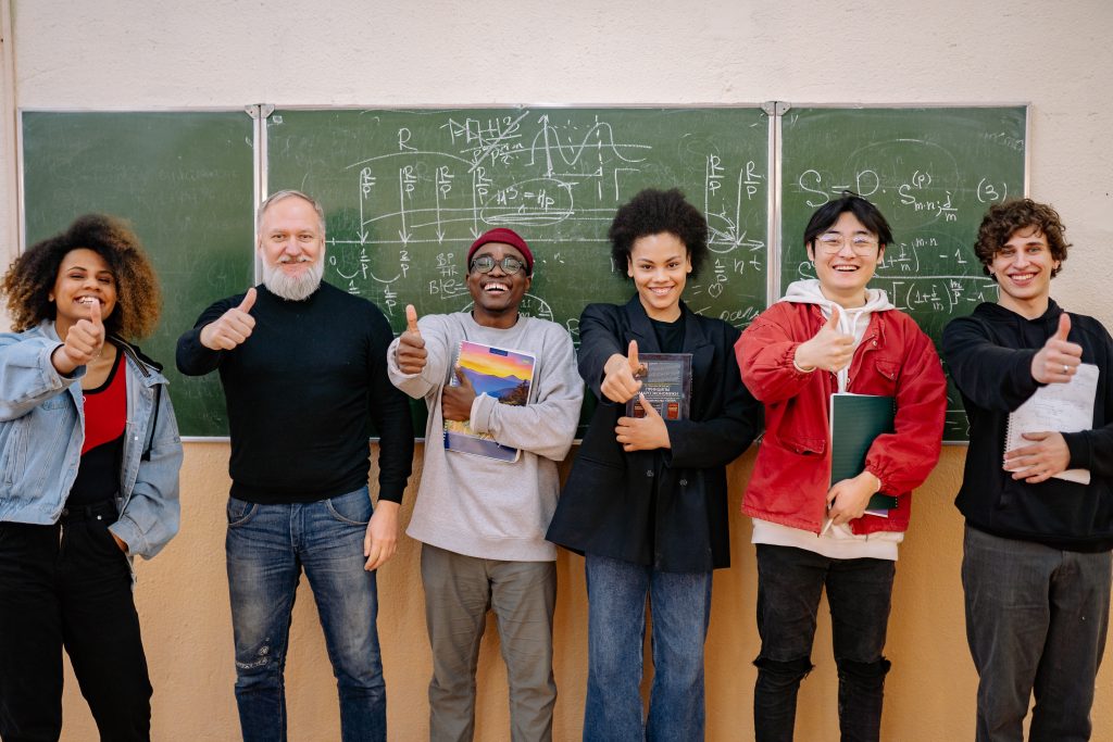 People giving thumbs up in front of a chalkboard