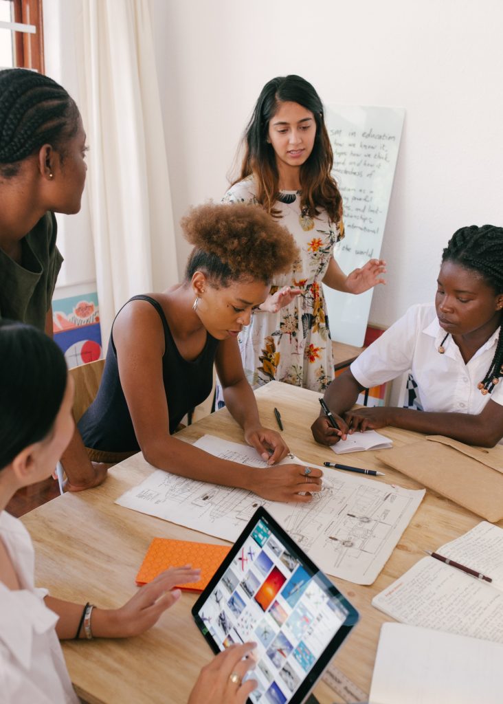 Group of students work together on a project around a large table. 