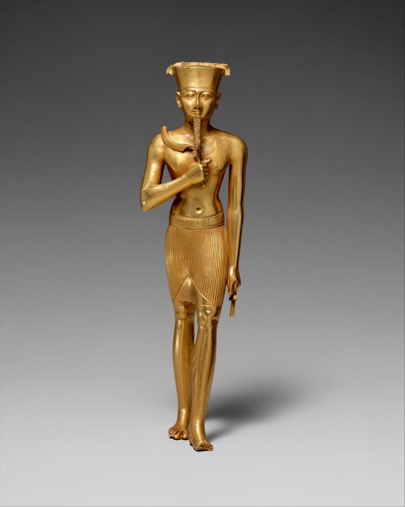 A golden statuette standing in an upright position holding an object