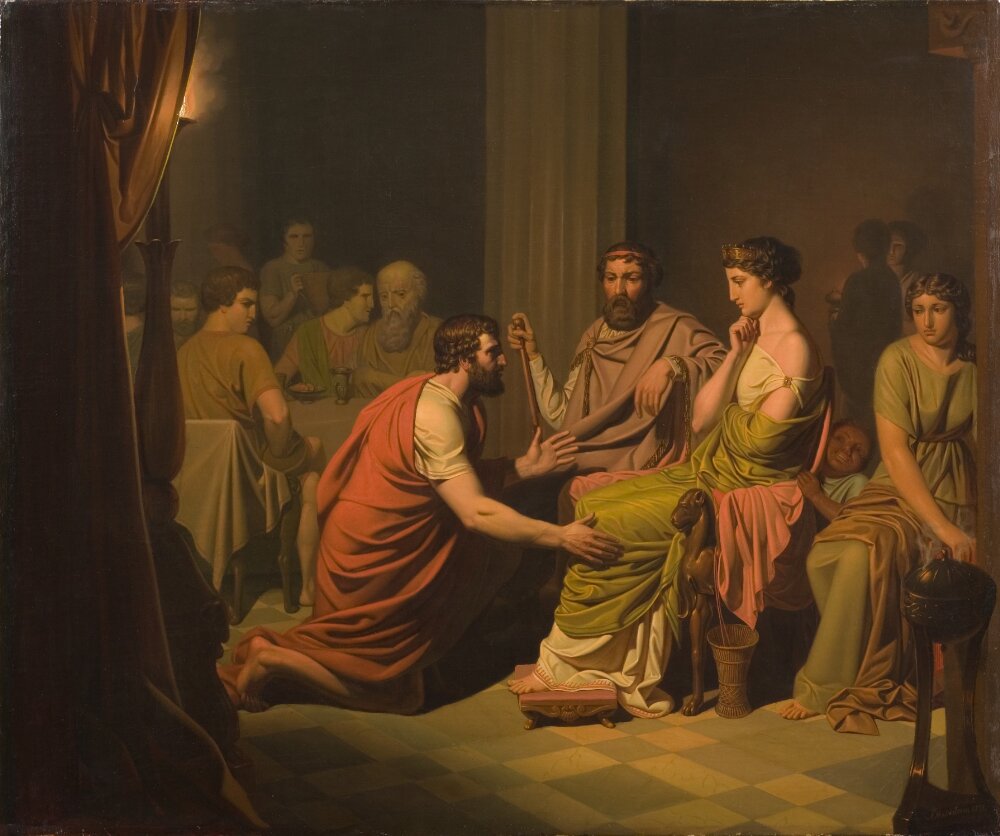 A painting of a crowded room with people. There is a focal point in the painting with three people. One of the people is leaned down as if giving an offering. The other two are aristocratic in their depiction. A king and a queen seated before the man.