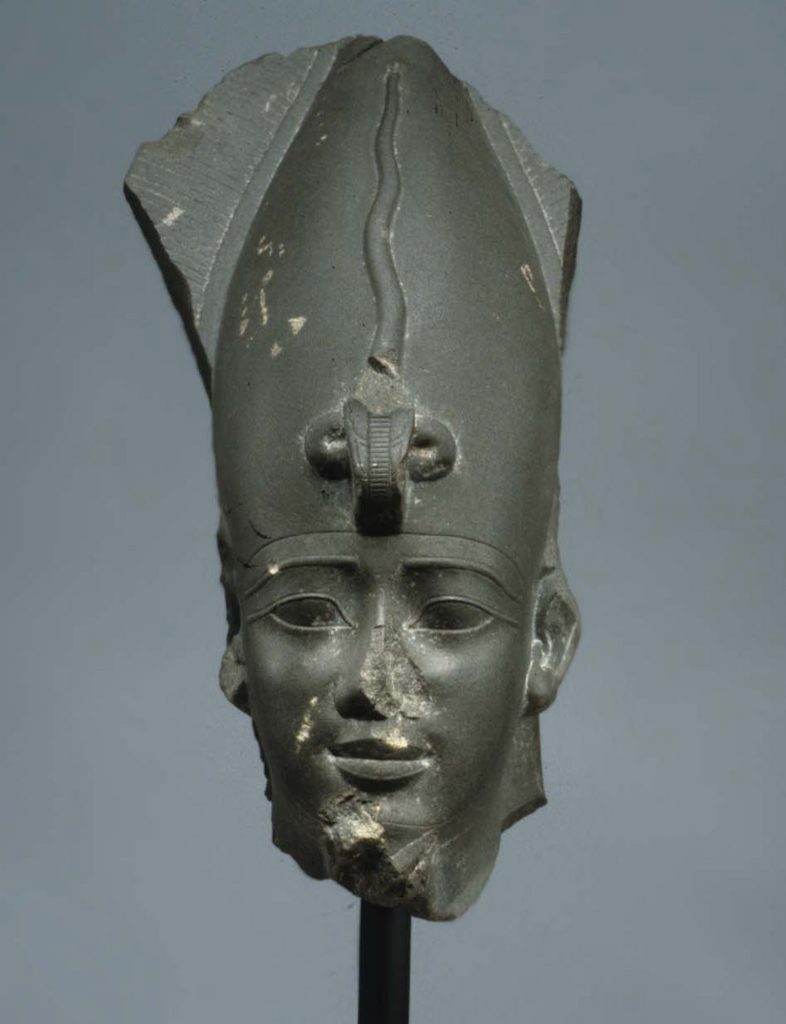 A depiction of a stone head wearing a hat that used to be attached to a body.