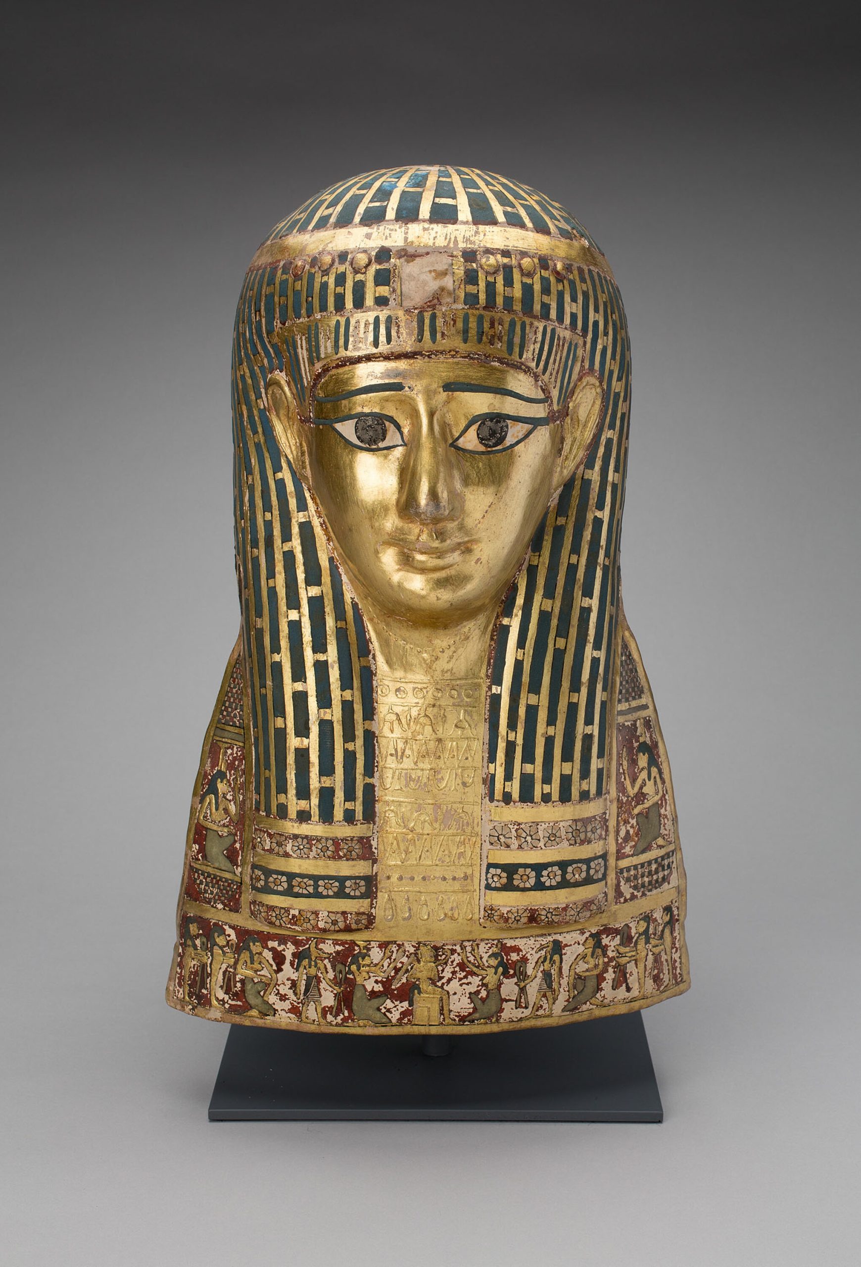 A mummy face cover with intricate gold and coloured details.