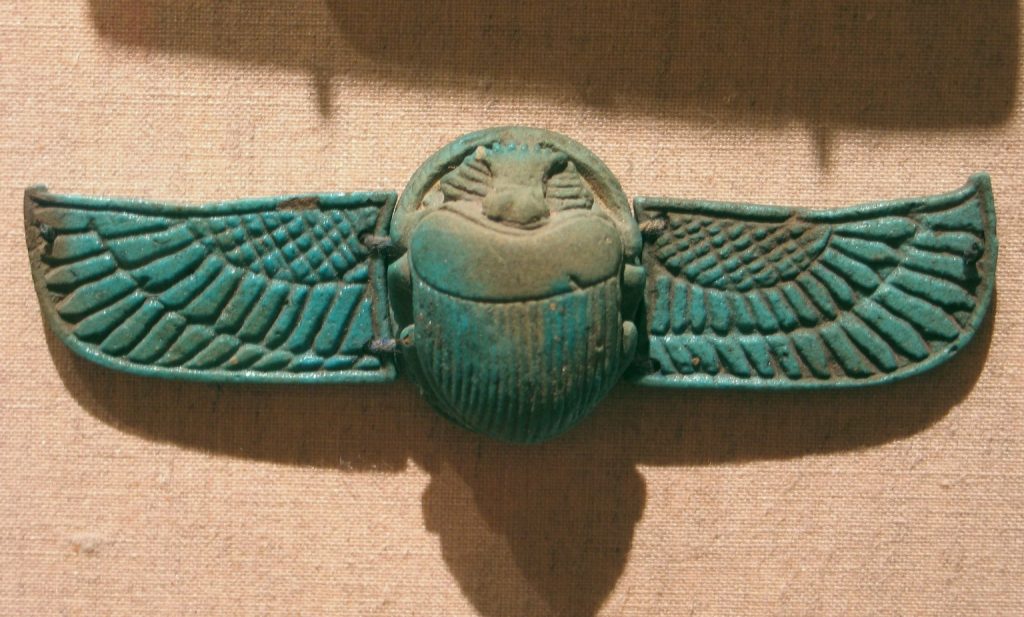 A stone carving of a scarab. The scarab is depicted with its wings spread. Faded turquoise in colour.