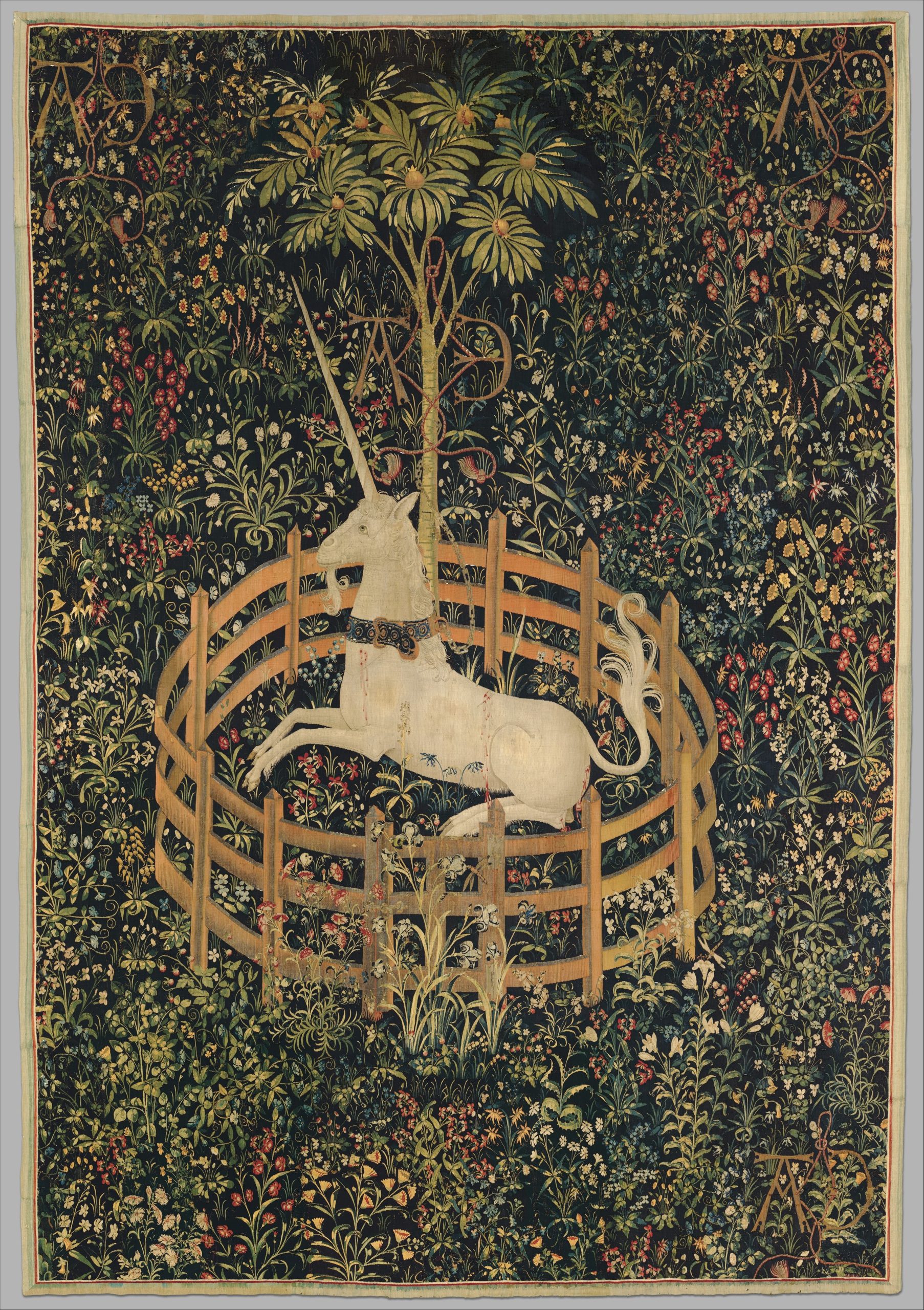 A woven tapestry details an image of a unicorn in a circular fence surrounded by patterns of flowers.