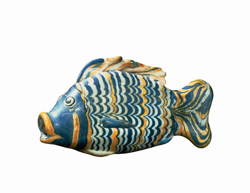 A glass bottle in the shape of a fish painted with rippling lines