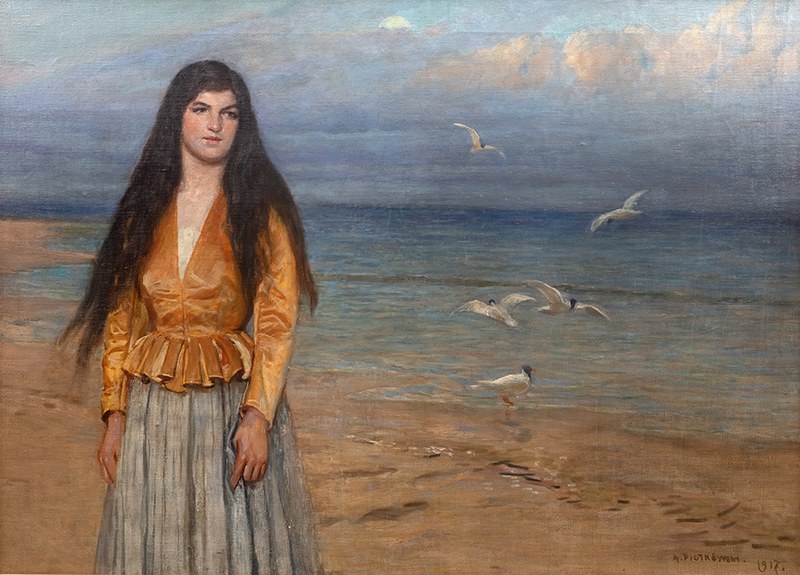 A young girl standing on the beach with seagulls in the background