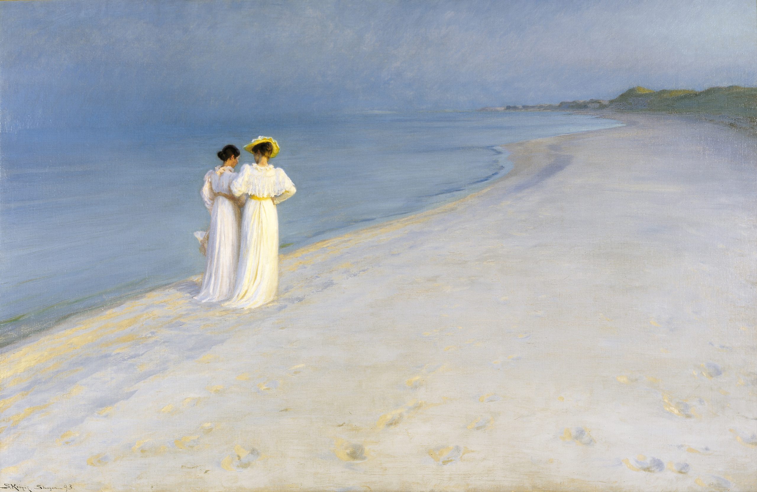 Two women in long dresses walking side-by-side along the beach