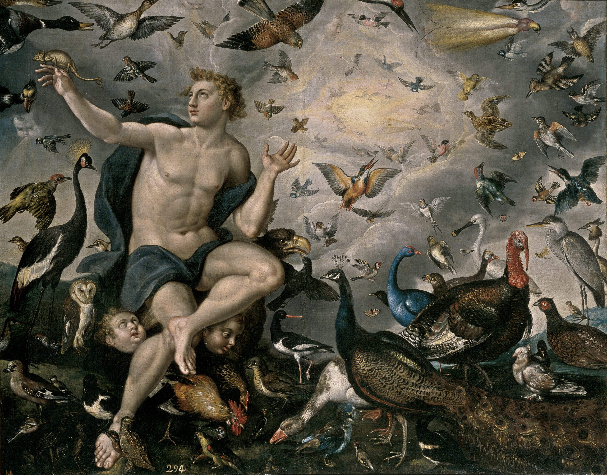 A man sits on a rock with his arms spread around him as a variety of birds in the air swarm him.