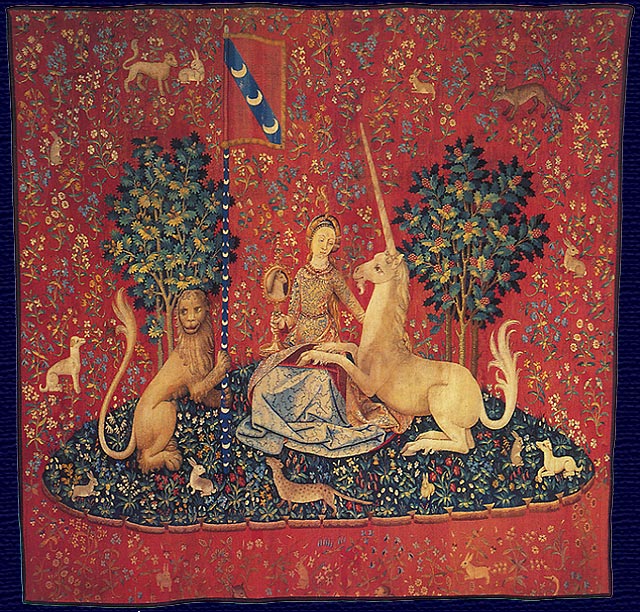 A tapestry details the image of a woman who sits between two trees with a unicorn, a lion, rabbits and other animals.