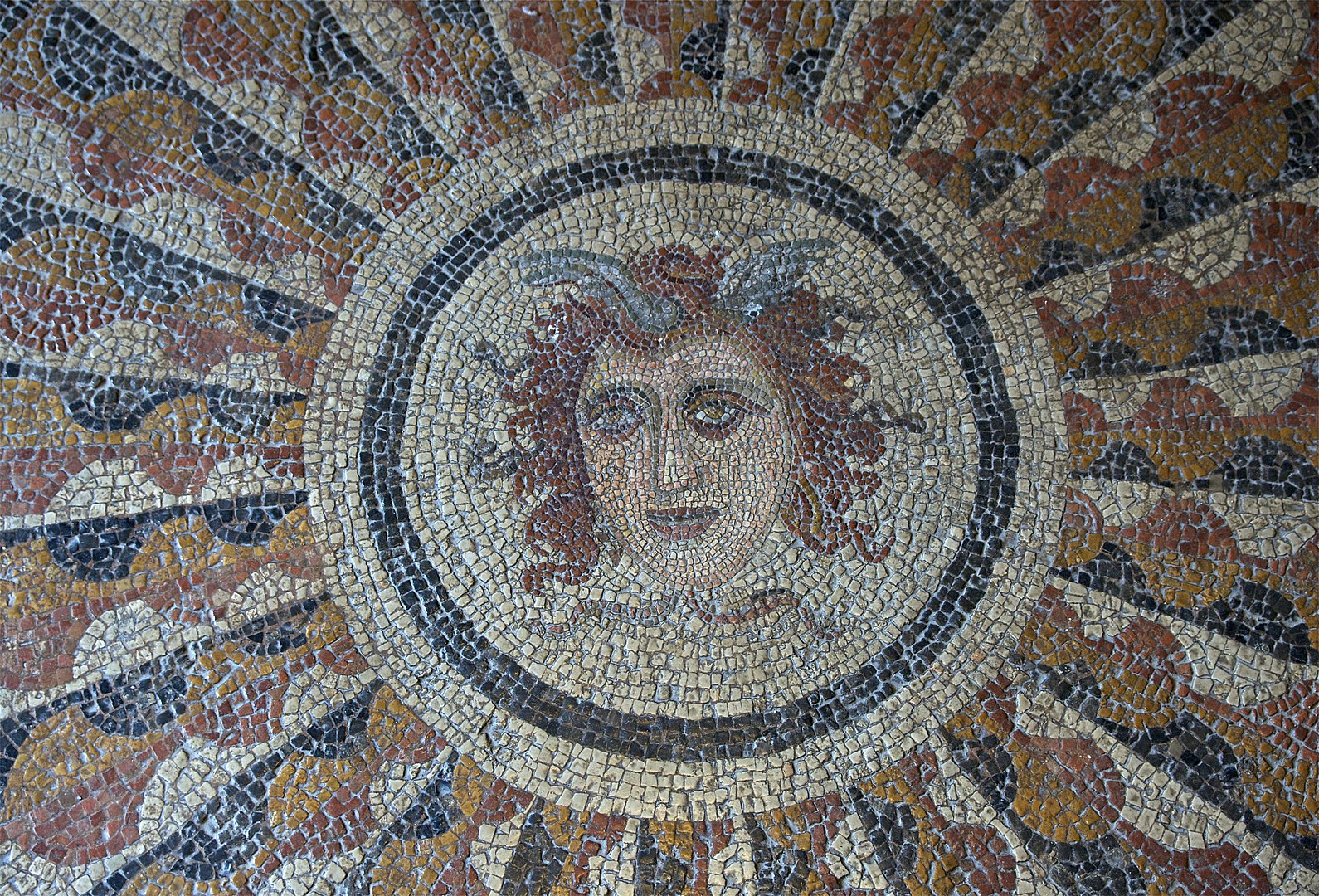 A large collection of mosaic tiles form a portrait of Medusa.