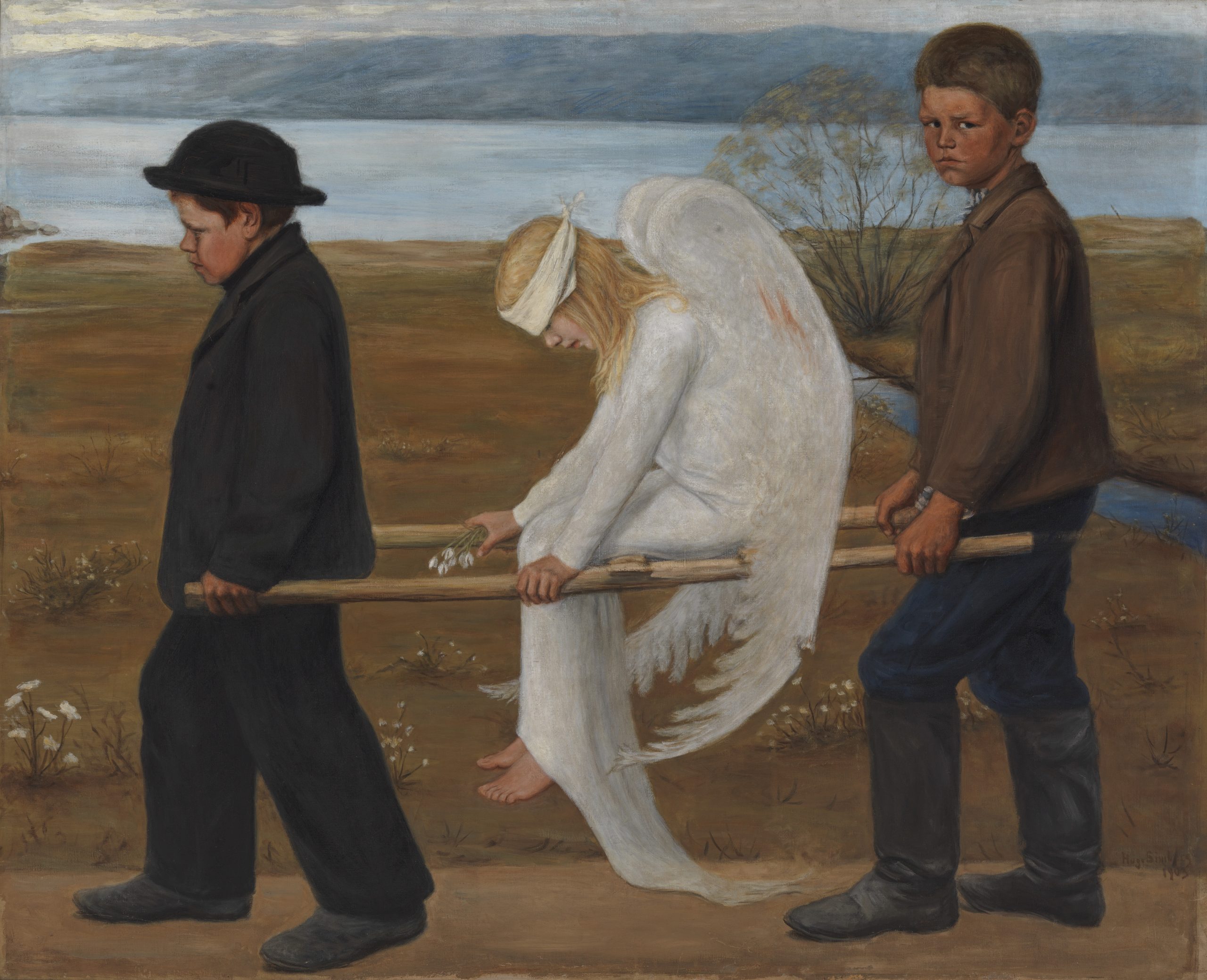 Two boys carry a fallen angel through a pathway next to a river.