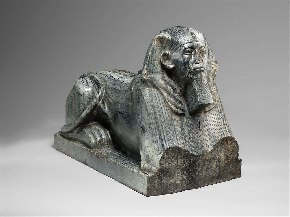 A iron sphinx laying prone sitting on a slab.