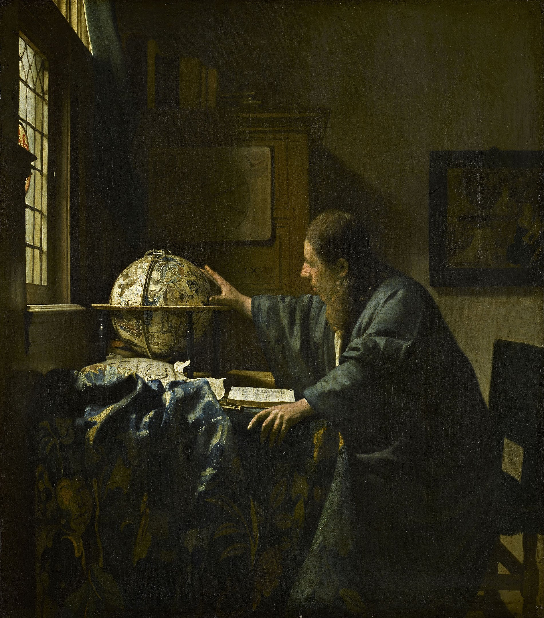 A man in sideview studying a globe on a table beside a window