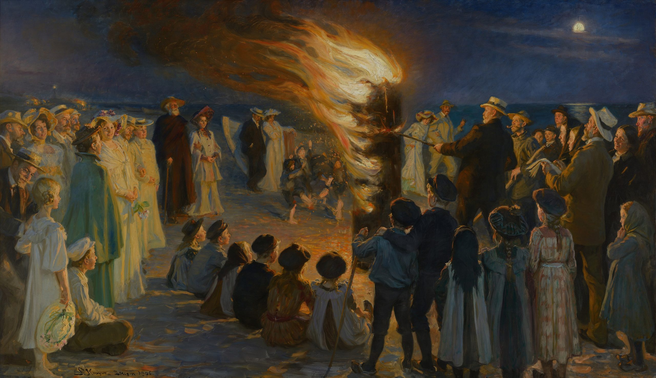 A large crowd of people gathered around a bonfire on a beach at night