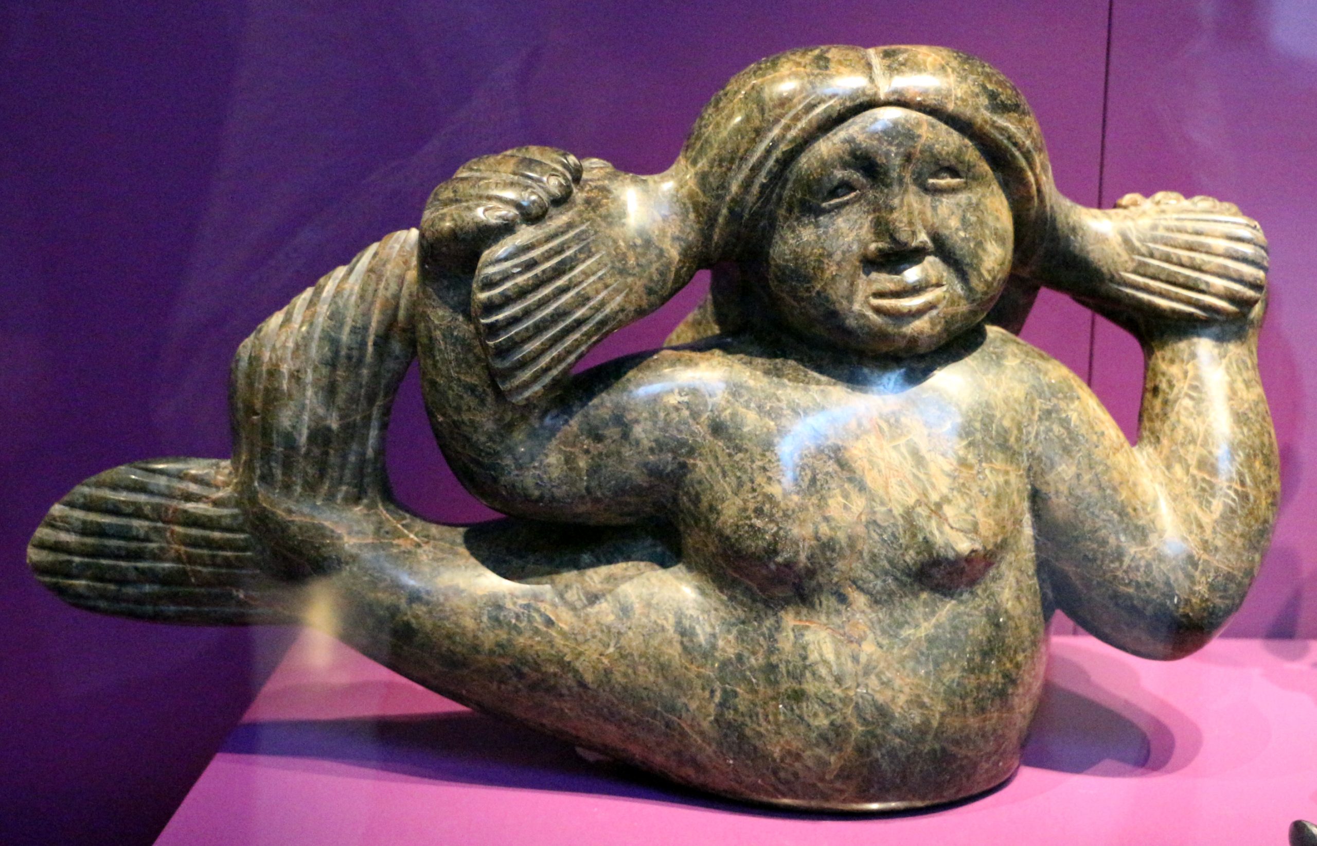 A sculpture depicting a mythical sea goddess. A woman's head, torso and arms with the tail of a sea creature.