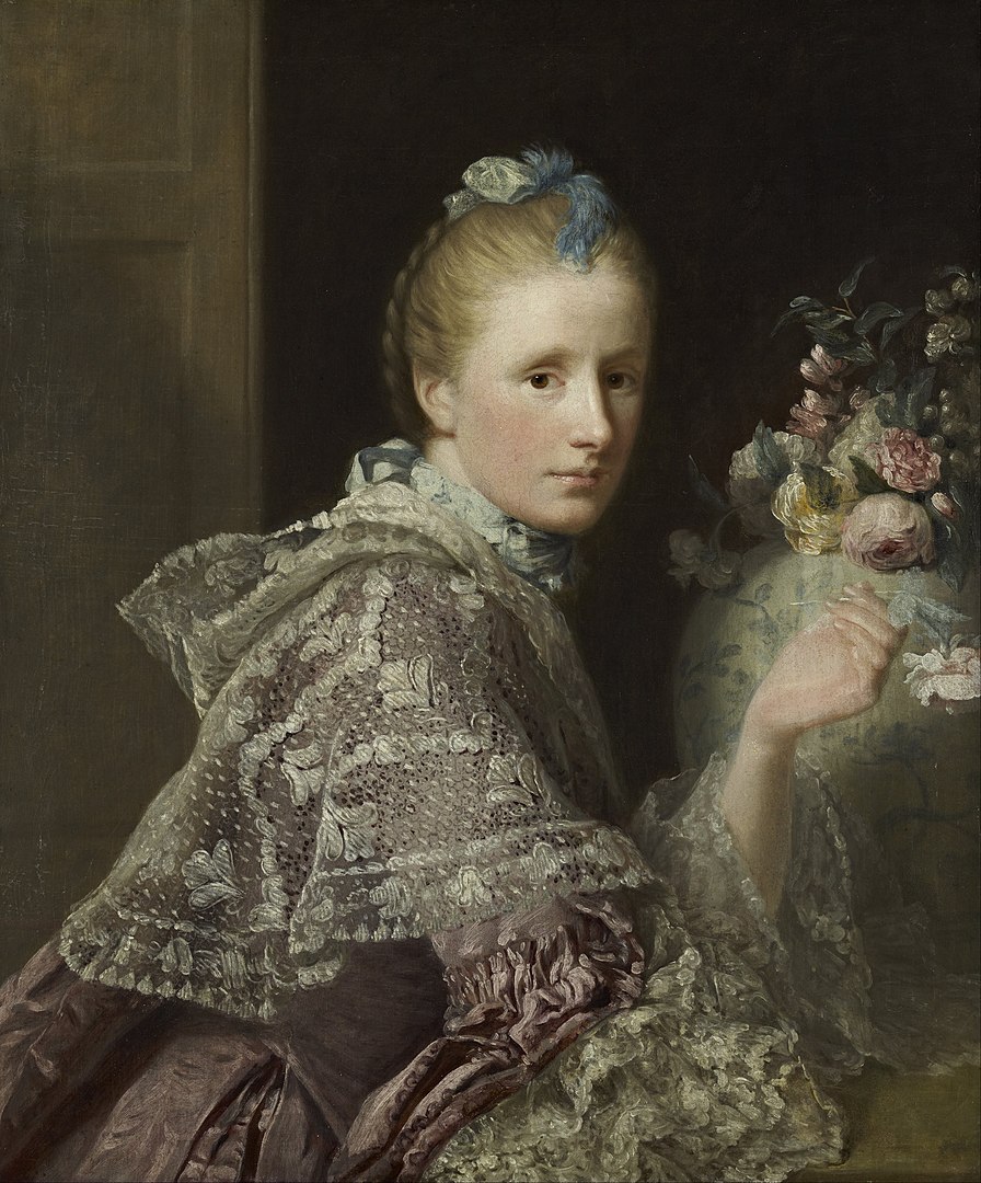 A portrait of a woman who sits next to a bouquet of flowers.