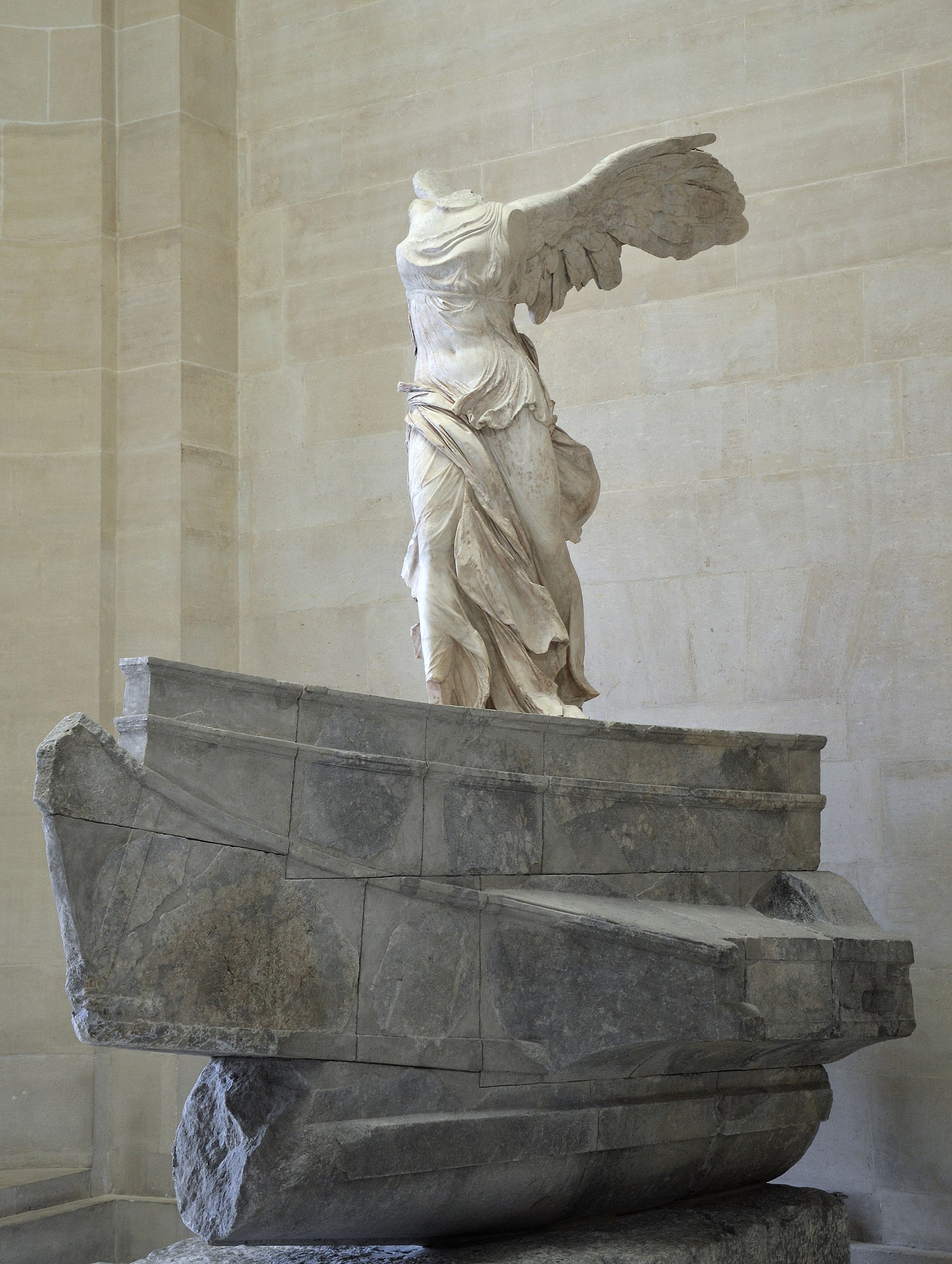 A headless statue of a winged female figure striding