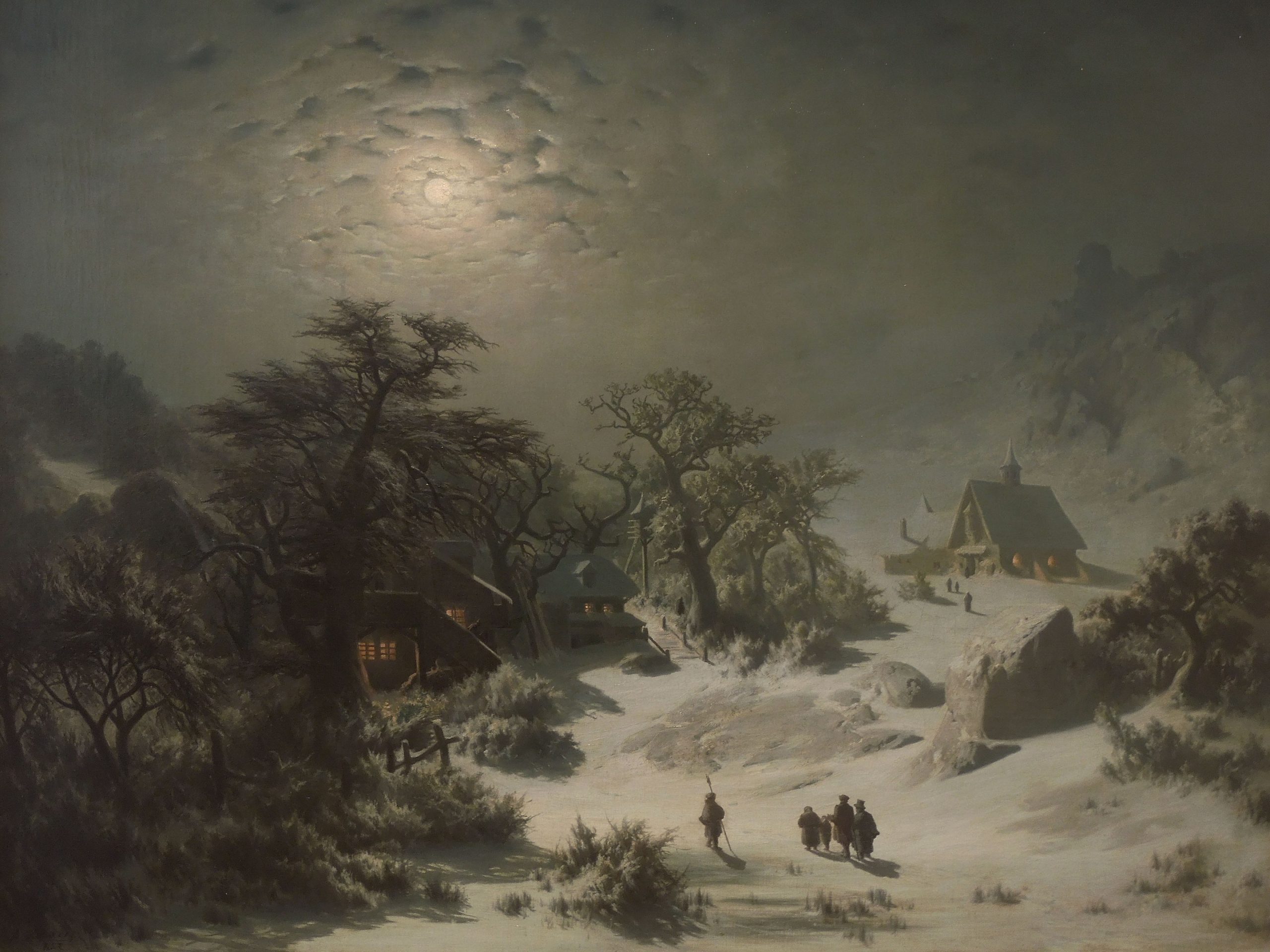 A landscape view of a snowy village with people walking at night