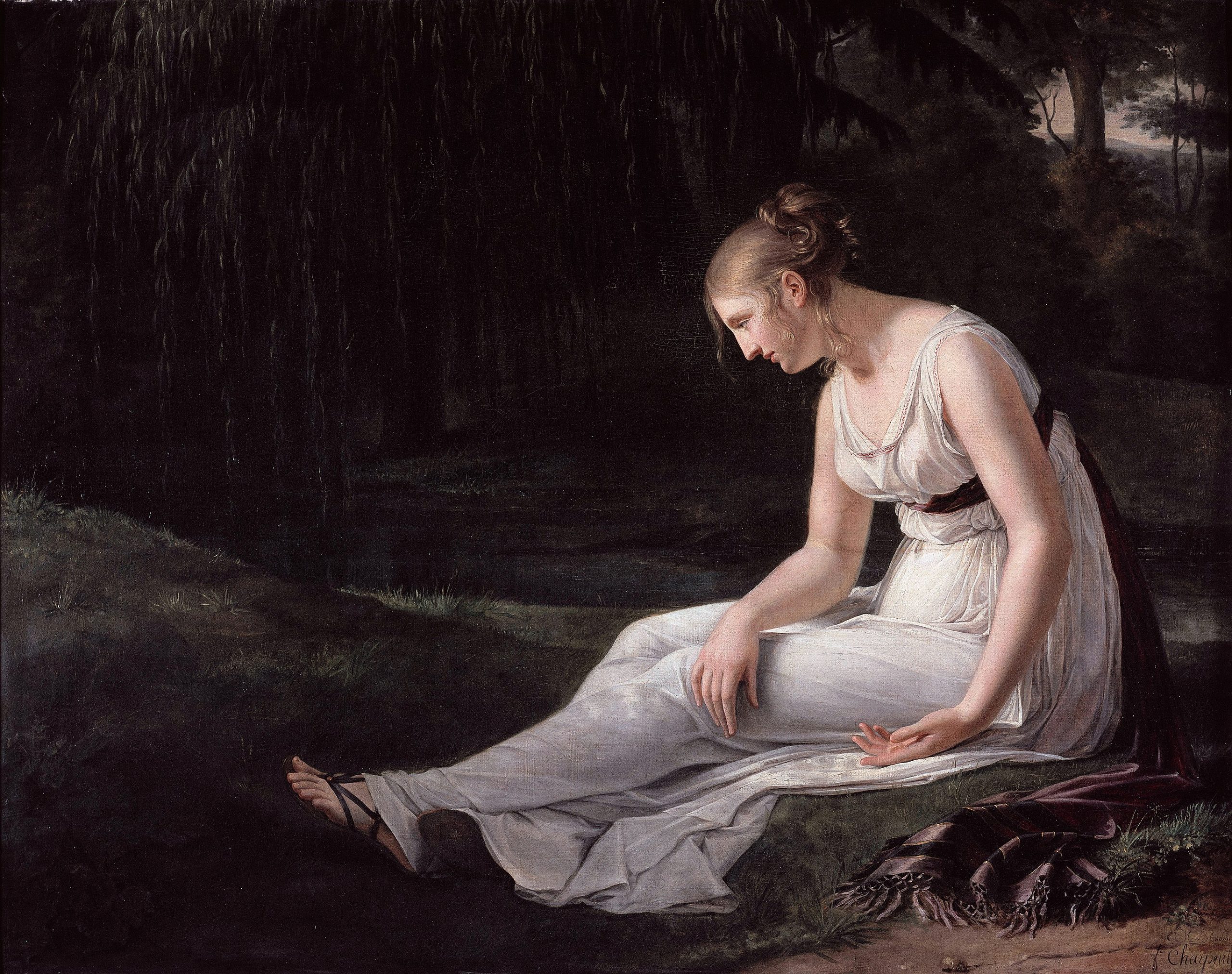 A woman sitting on the grass in the forest with a piece of fabric at her side