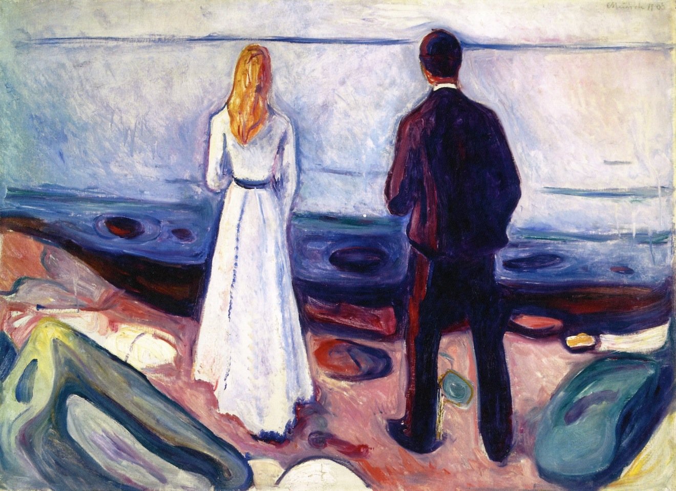 A man and woman standing side-by-side looking out at sea