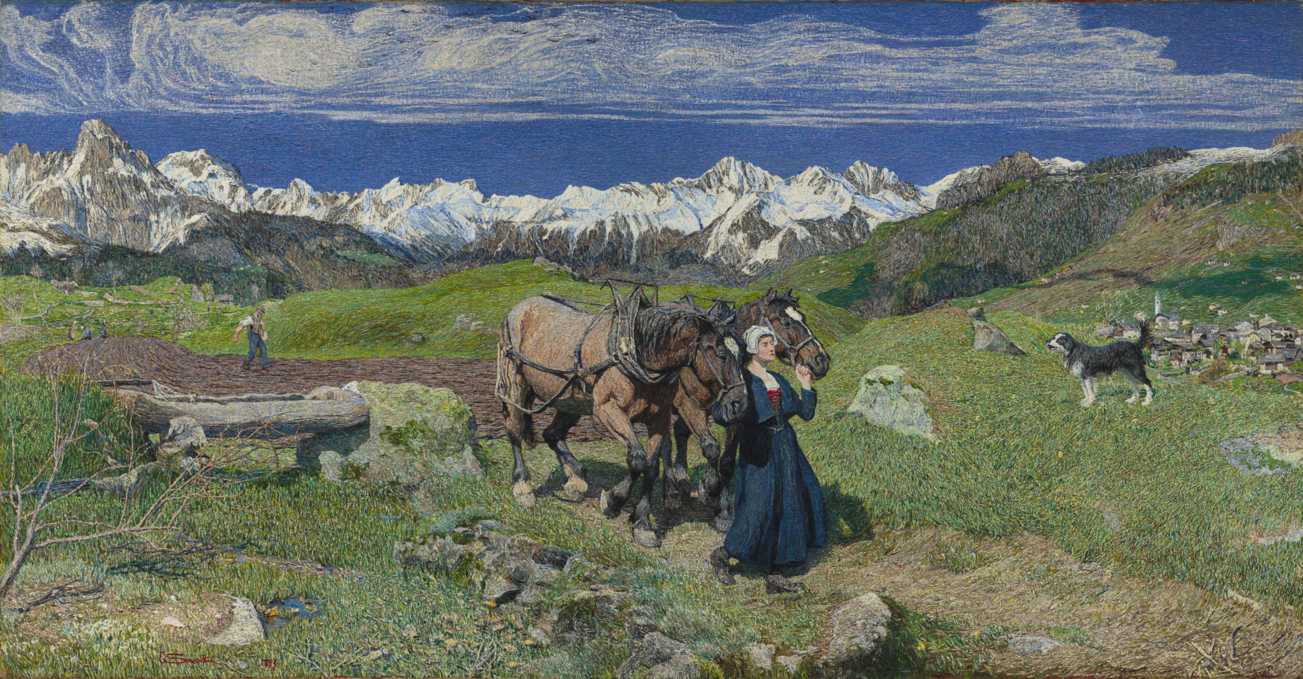 A woman walking two horses across a field with snow-peaked mountains in the background