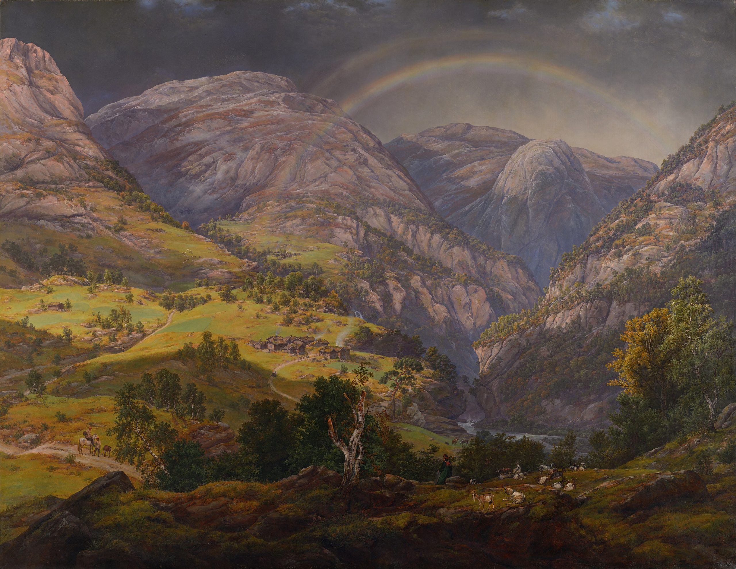 A landscape view of a rainbow spanning across several mountains