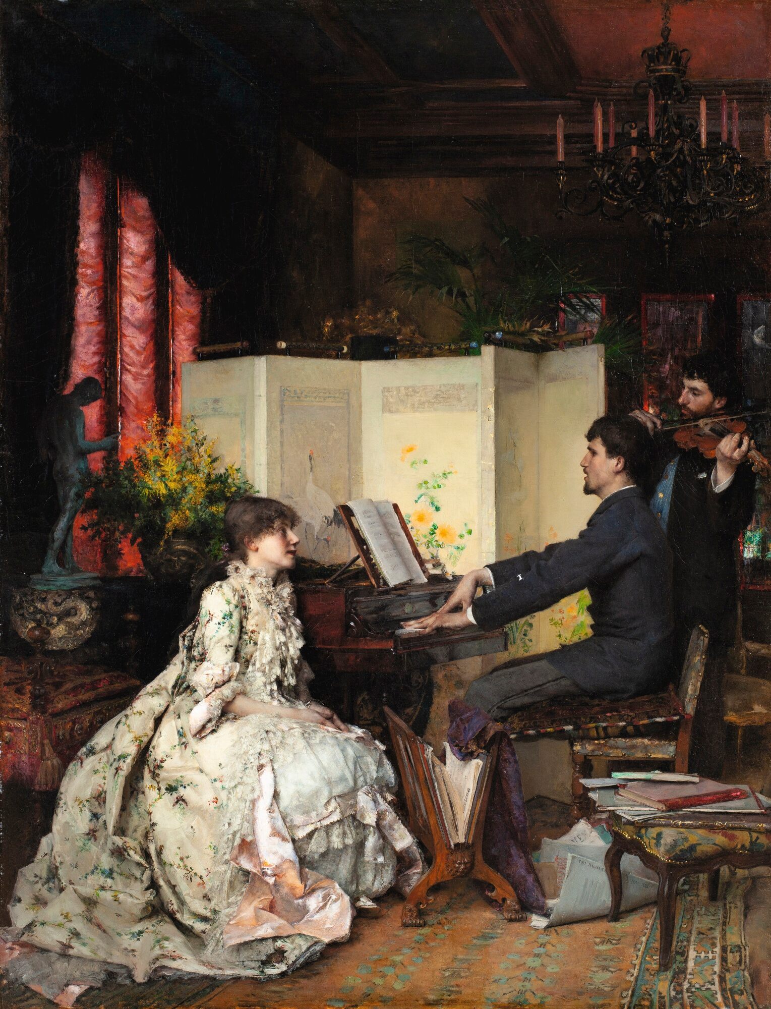 A woman in a dress sitting across from a man playing the piano enclosed by a folding screen in a room with a violinist nearby