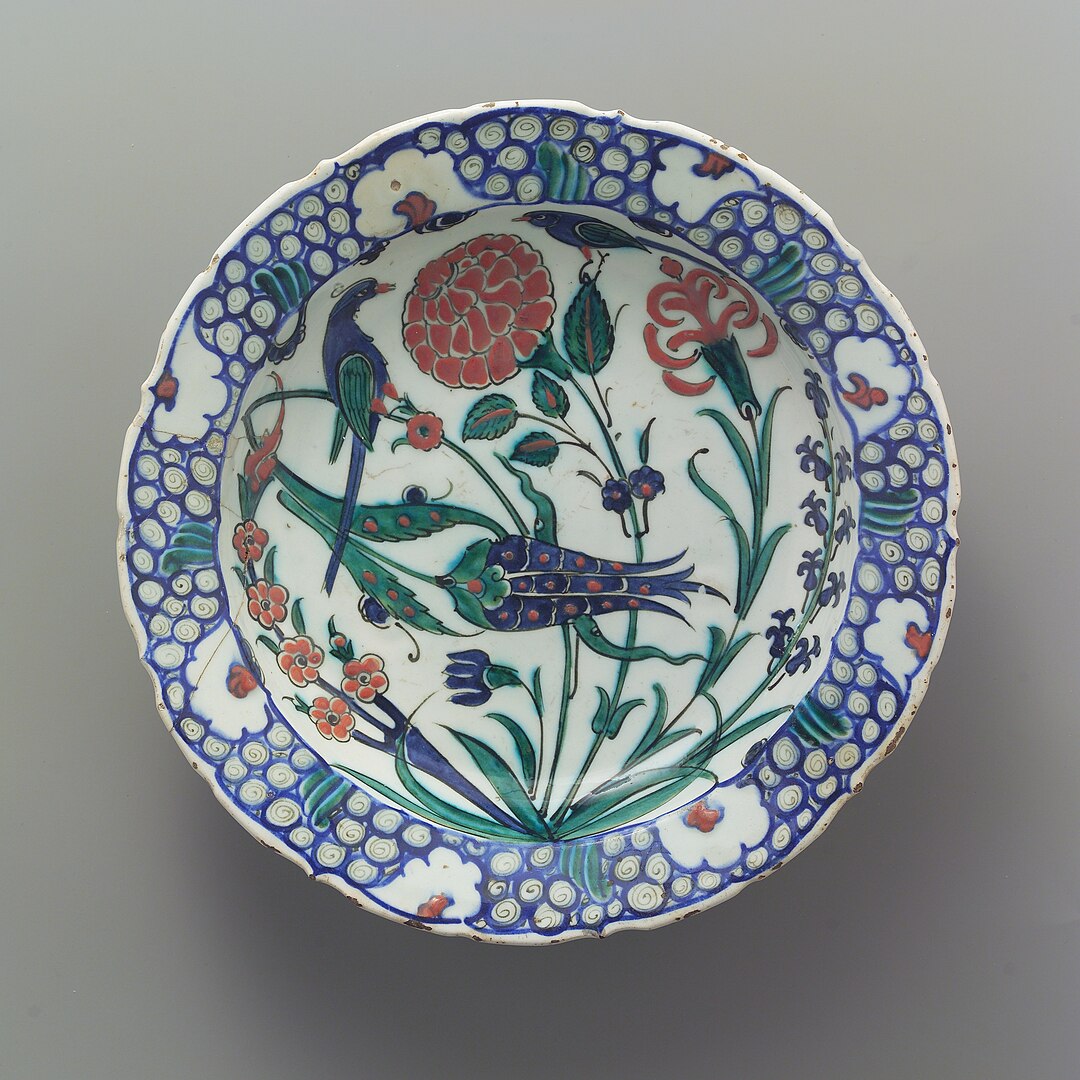 A ceramic dish depicting two birds among flowering plants