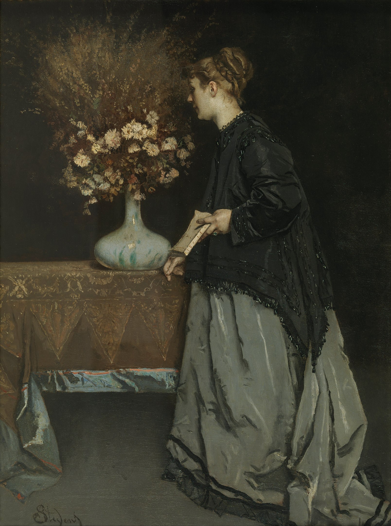 A woman carrying a book observing a vase of flowers on a table