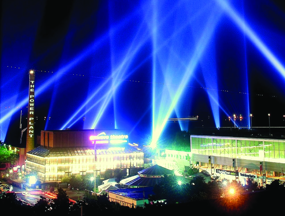 This is a photo of searchlight beams in the night sky of a city scene.